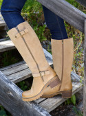 Bota de cuero camel para mujer, caña alta casi hasta la rodilla, con cierre lateral y hebilla decorativa ajustable.