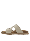 Detalle de las correas de cuero liso y hebillas metálicas sobre la sandalia beige.