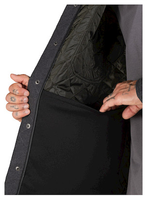 Detalle de cierre con broches metálicos en chaqueta de hombre, aportando un look urbano y funcional.